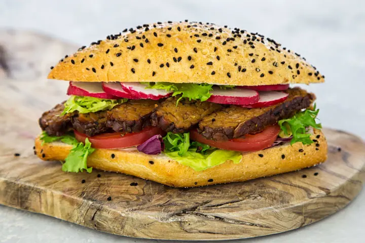 Burger avec galette de tempeh et garniture de laitue, tomates et radis