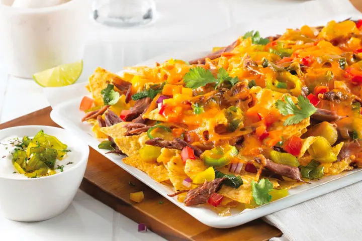 Recipe for homemade nachos with duck confit, leeks and cheese as garnish