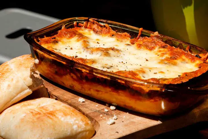 Lunch box cheese and meat lasagna with a side of bread