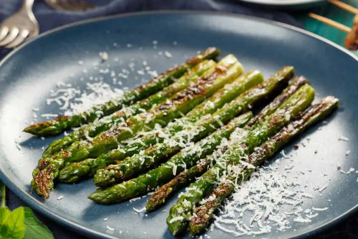 Assiette d’asperges grillées avec du fromage parmesan râpé en garniture