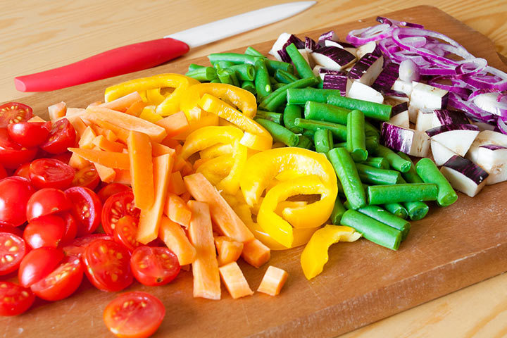 Tomatoes, carrots, peppers, beans, eggplant and onions cutted on a wooden board