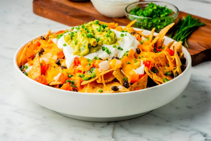 Recipe for best homemade nachos all topped with guacamole and sour cream on top