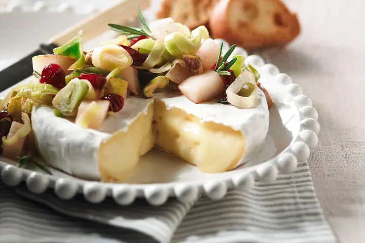 Oven‑baked fondant brie with leeks and dried fruits on top