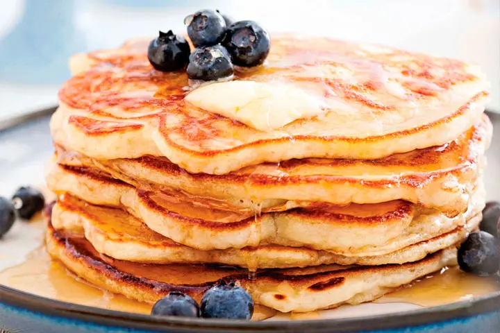 Banana pancakes with blueberries and maple syrup topping for a traditional brunch recipe