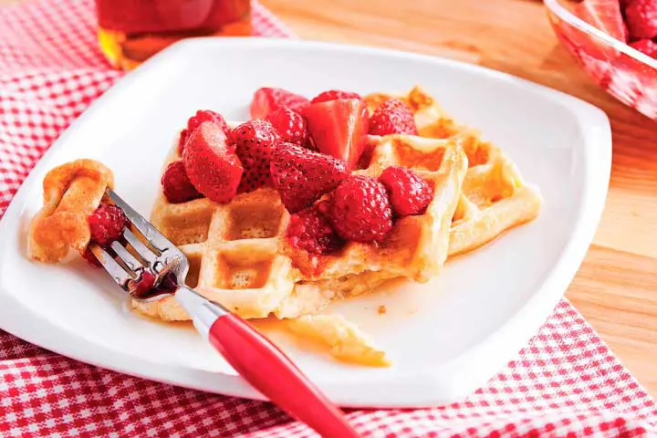 Classic waffles topped with strawberries, raspberries and maple syrup for a traditional brunch recipe