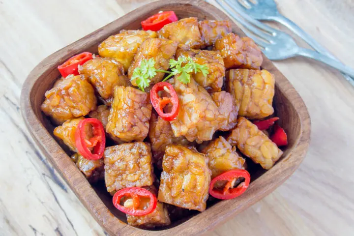 Orange-glazed tempeh cubes with sliced hot peppers